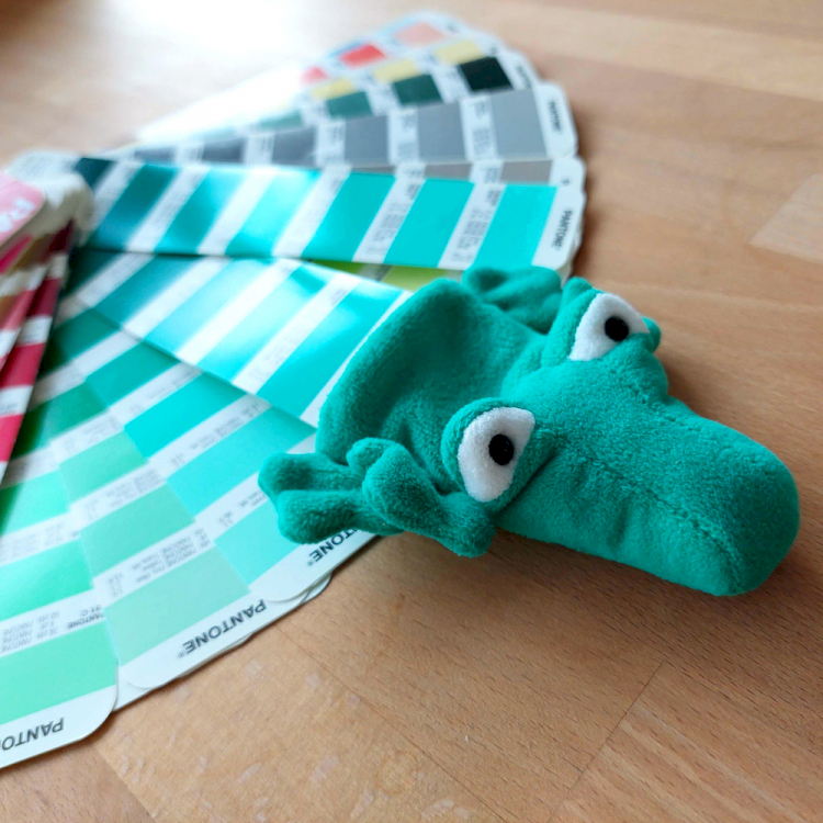 typneun Maskottchen Pantoni: Stofftier-Krokodil auf Pantone-Farbfächern